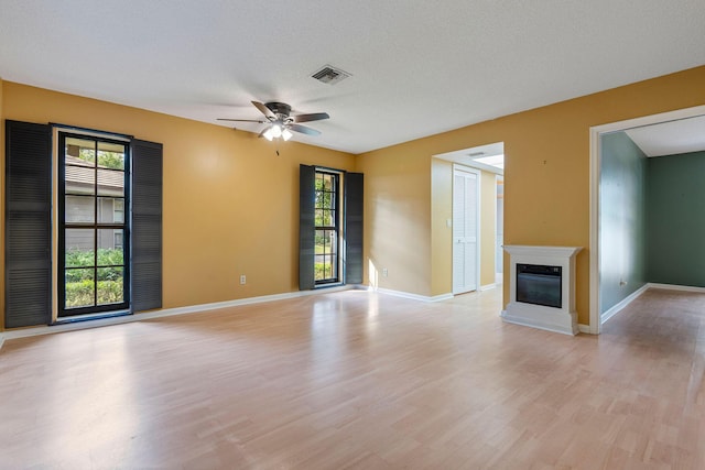 unfurnished living room with a textured ceiling, ceiling fan, and light hardwood / wood-style flooring