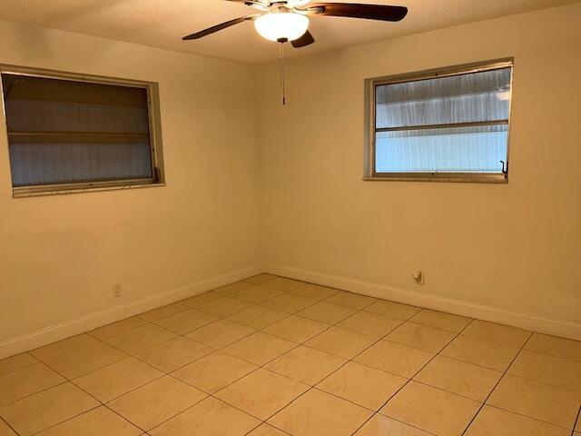 tiled spare room with ceiling fan