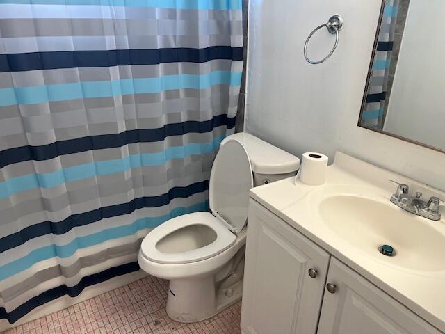 bathroom with tile patterned floors, curtained shower, vanity, and toilet