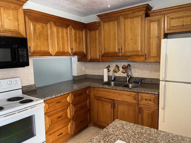 kitchen with sink, a textured ceiling, white appliances, decorative backsplash, and light tile patterned floors