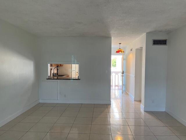 empty room featuring sink, light tile patterned floors, and a textured ceiling