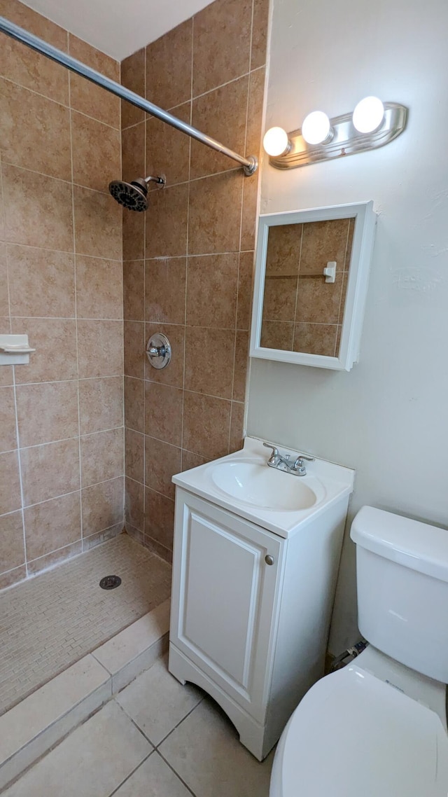 bathroom with tile patterned floors, vanity, toilet, and tiled shower