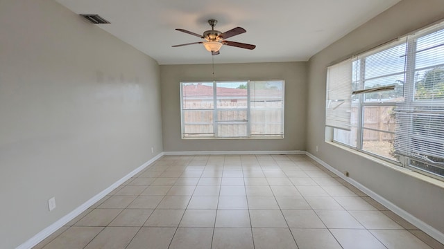 tiled empty room with ceiling fan and a healthy amount of sunlight