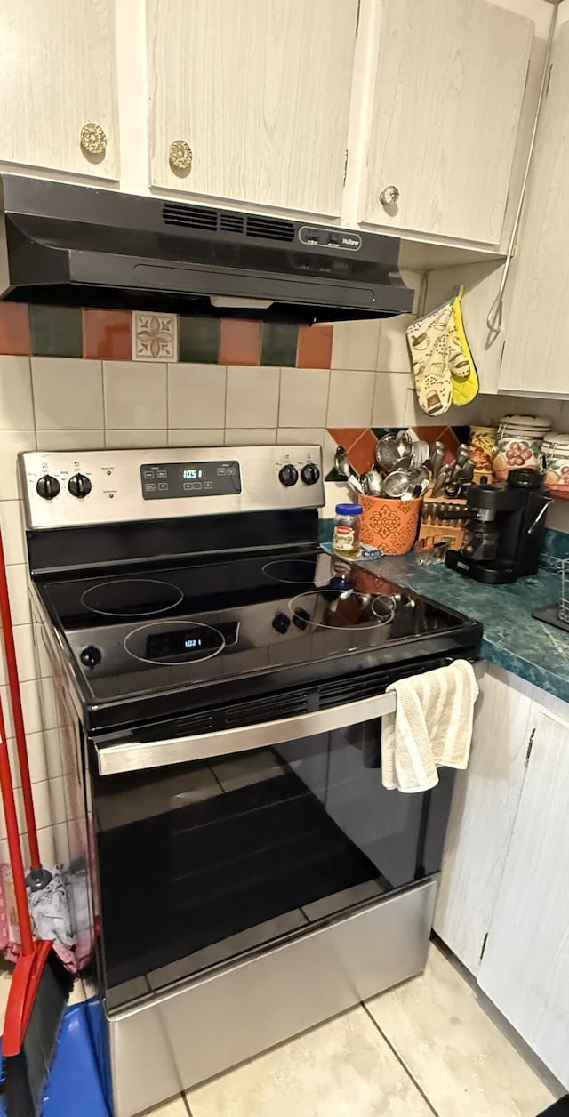 kitchen with decorative backsplash, light brown cabinetry, stainless steel range with electric cooktop, and light tile patterned flooring