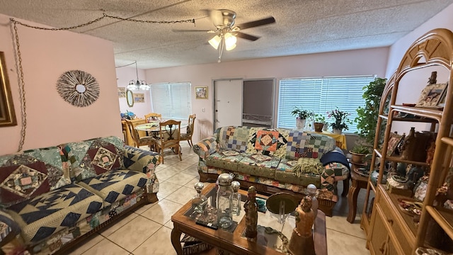 living room with ceiling fan with notable chandelier, light tile patterned flooring, and a textured ceiling