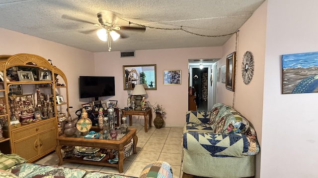 living room with ceiling fan, light tile patterned flooring, and a textured ceiling