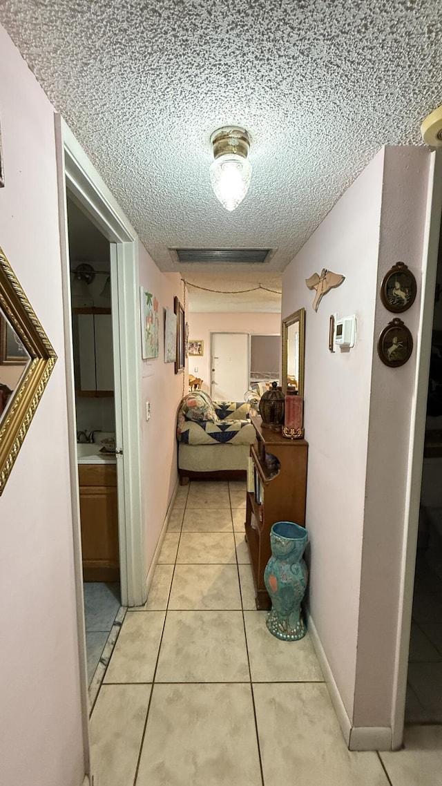 hallway featuring light tile patterned floors and a textured ceiling