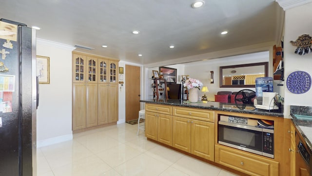 kitchen with dark stone countertops, light tile patterned flooring, black appliances, and ornamental molding