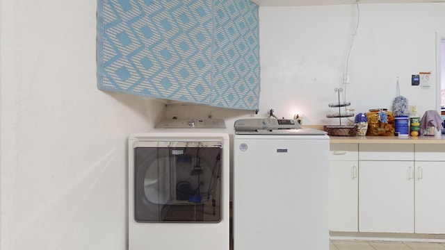 clothes washing area featuring washer and clothes dryer and cabinets