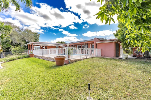 rear view of property with a lawn and a pool