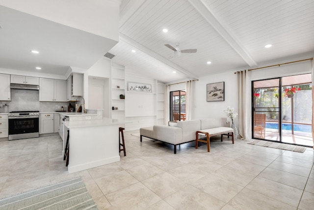 kitchen featuring a breakfast bar, lofted ceiling with beams, stainless steel stove, plenty of natural light, and kitchen peninsula