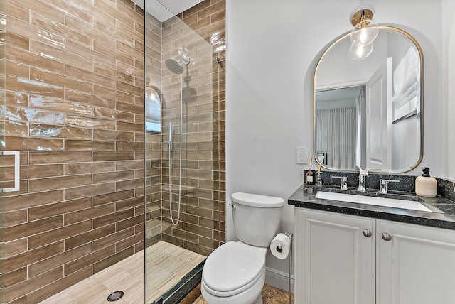 bathroom featuring vanity, toilet, and a tile shower