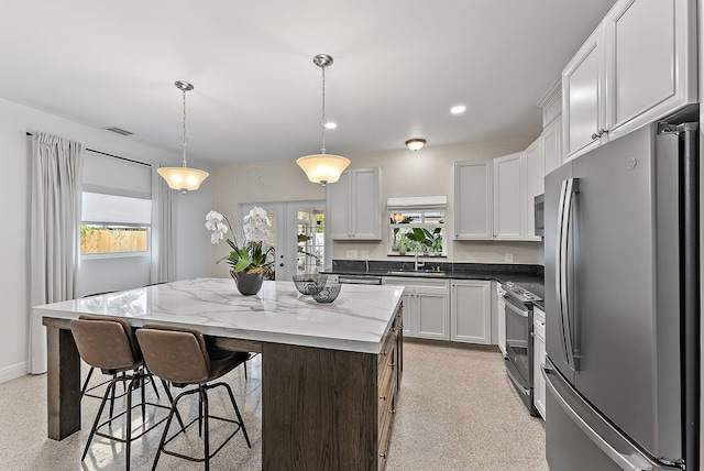 kitchen featuring a wealth of natural light, stainless steel appliances, white cabinets, a center island, and hanging light fixtures