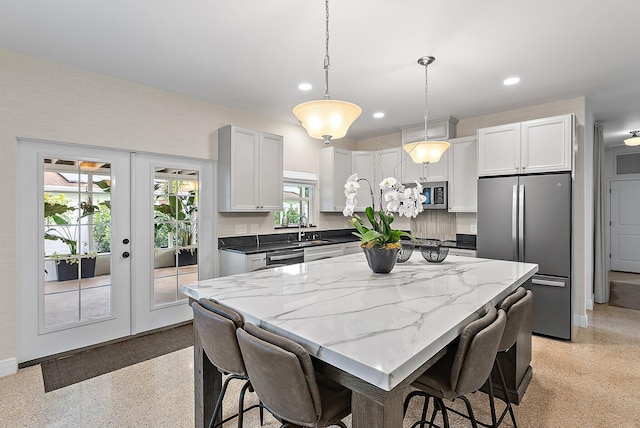 513 E Whitney Dr, Jupiter, FL 33458 - kitchen with appliances with stainless steel finishes, recessed lighting, dark aggregate flooring, light stone countertops, and french doors