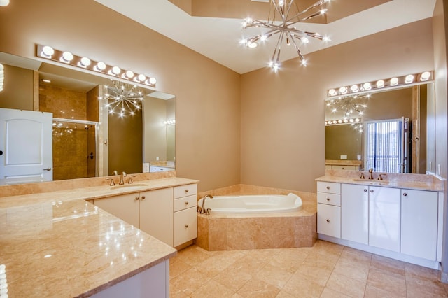 full bath featuring a chandelier, a stall shower, a garden tub, two vanities, and tile patterned floors