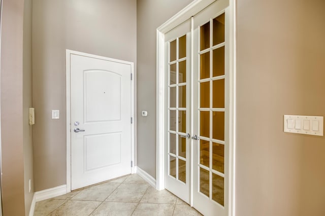 doorway to outside with french doors, light tile patterned floors, and baseboards