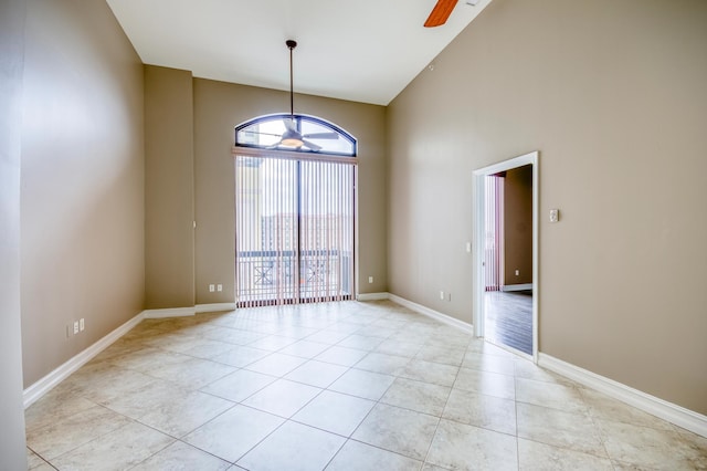 empty room with high vaulted ceiling, light tile patterned flooring, and ceiling fan