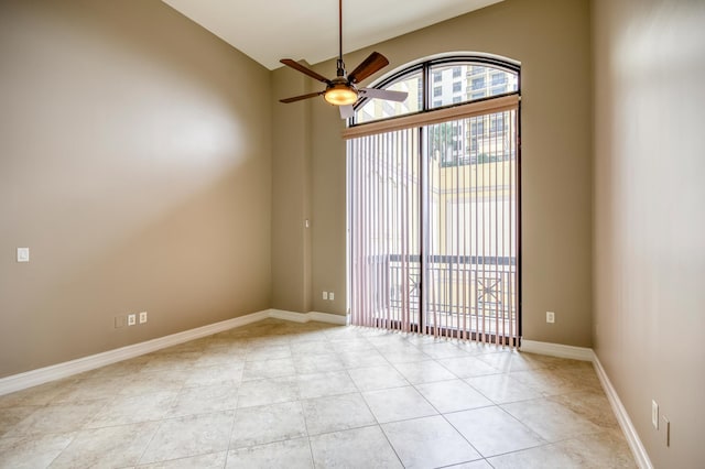 spare room with plenty of natural light, a ceiling fan, light tile patterned floors, baseboards, and high vaulted ceiling