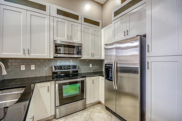 kitchen with stainless steel appliances, a sink, decorative backsplash, and white cabinets