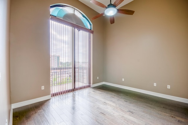 spare room featuring healthy amount of natural light, a ceiling fan, wood finished floors, and baseboards