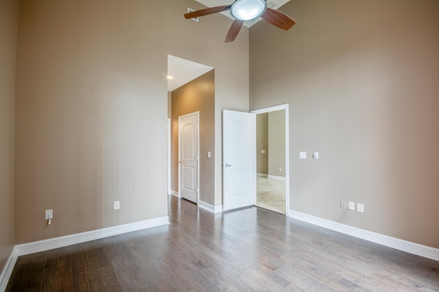 spare room with a high ceiling, ceiling fan, baseboards, and wood finished floors