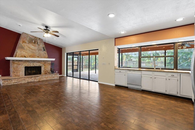 unfurnished living room featuring sink, dark wood-type flooring, a fireplace, a textured ceiling, and vaulted ceiling