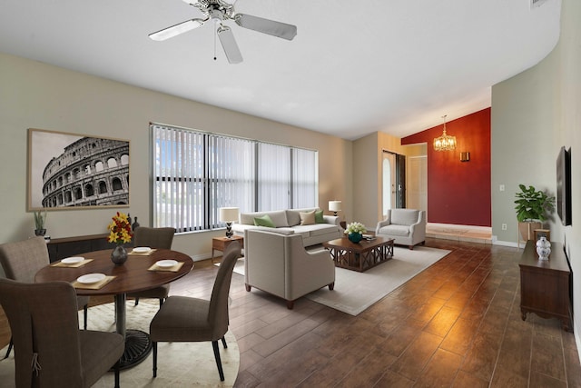 living room featuring lofted ceiling, ceiling fan with notable chandelier, and dark wood-type flooring