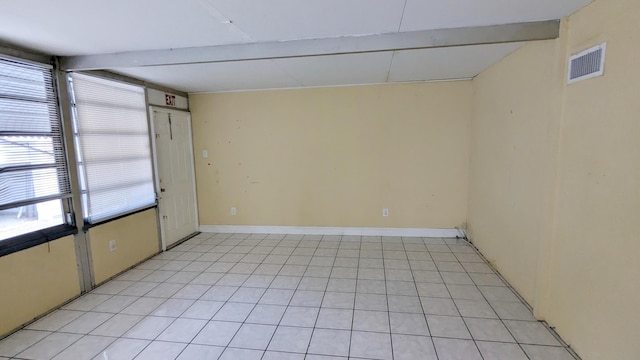 empty room featuring plenty of natural light and beamed ceiling