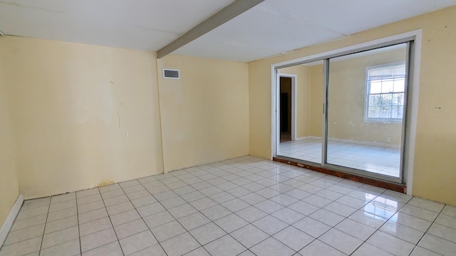 spare room with beam ceiling and light tile patterned floors