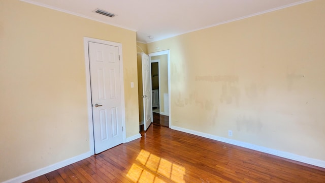 empty room with wood-type flooring and crown molding