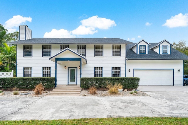 colonial home with a chimney, concrete driveway, and a garage