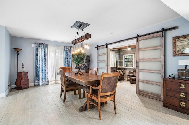 dining space with a barn door and light wood-type flooring