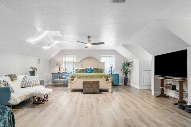 bedroom featuring ceiling fan, lofted ceiling, light hardwood / wood-style flooring, and a textured ceiling