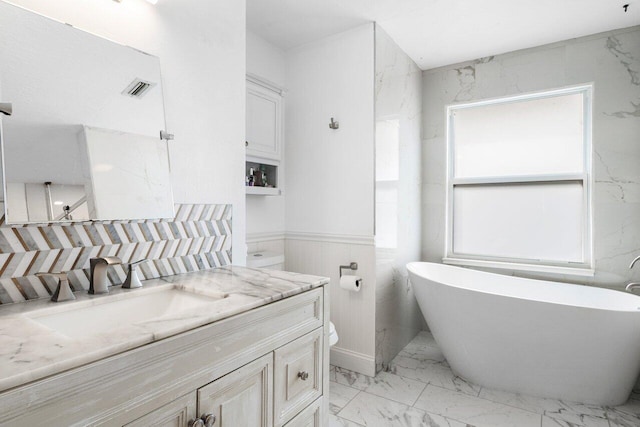 bathroom with a bathtub, vanity, tile walls, and toilet