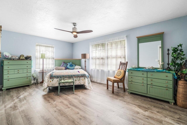 bedroom with ceiling fan, a textured ceiling, and light wood-type flooring