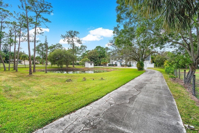 surrounding community with a water view, a storage shed, and a lawn