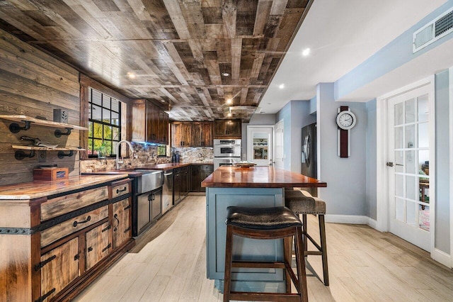 kitchen featuring sink, wood ceiling, a kitchen island, light hardwood / wood-style floors, and decorative backsplash