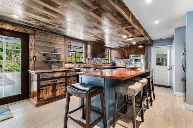 kitchen with tasteful backsplash, butcher block countertops, dark brown cabinets, and light hardwood / wood-style floors