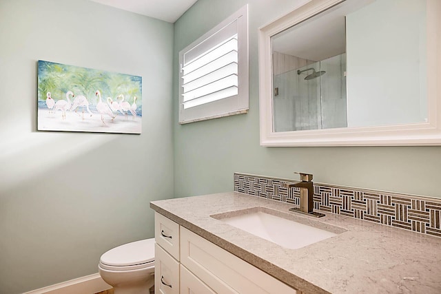 bathroom with vanity, toilet, walk in shower, and tasteful backsplash