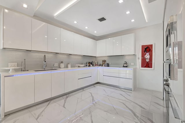 kitchen with white cabinets, sink, and tasteful backsplash