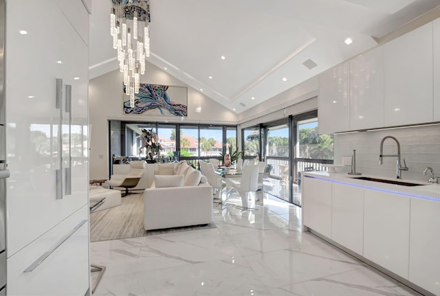 living room with sink, high vaulted ceiling, and a chandelier