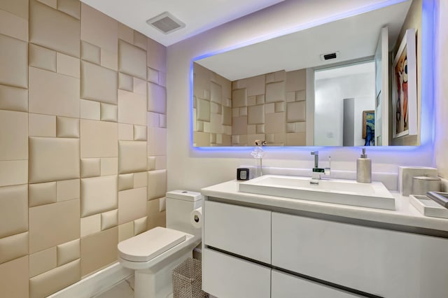 bathroom featuring vanity, toilet, and tasteful backsplash