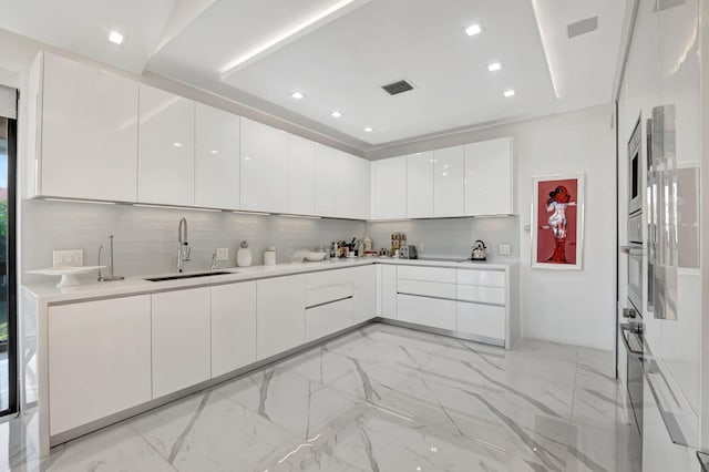 kitchen featuring decorative backsplash, stainless steel oven, white cabinetry, and sink