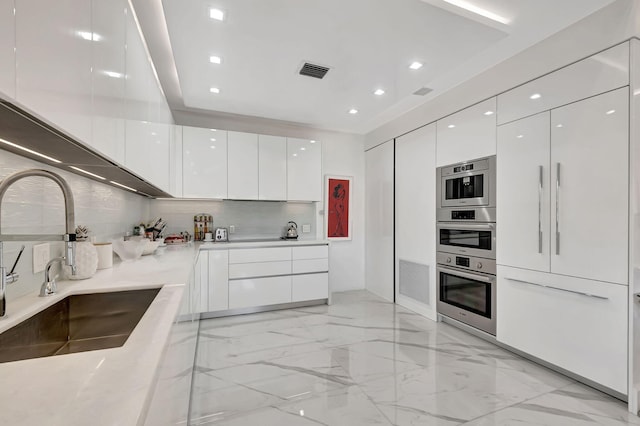 kitchen with backsplash, sink, white cabinets, and stainless steel double oven