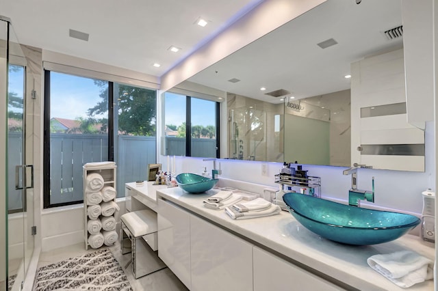 bathroom with tile patterned flooring, plenty of natural light, walk in shower, and vanity