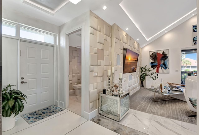 entrance foyer with lofted ceiling, tile walls, and a healthy amount of sunlight