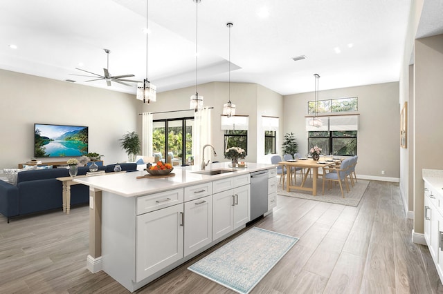 kitchen with white cabinets, dishwasher, open floor plan, light countertops, and a sink