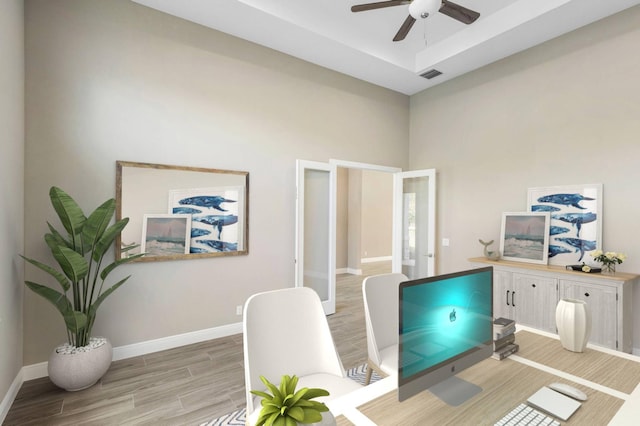 office with ceiling fan, visible vents, baseboards, light wood finished floors, and a raised ceiling