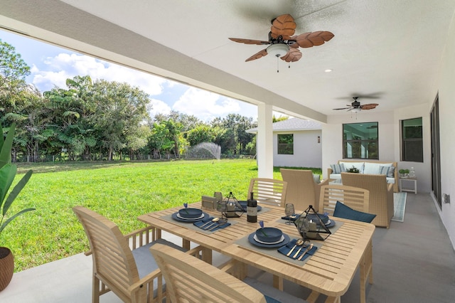 view of patio / terrace featuring outdoor dining space, a ceiling fan, and an outdoor living space with a fire pit