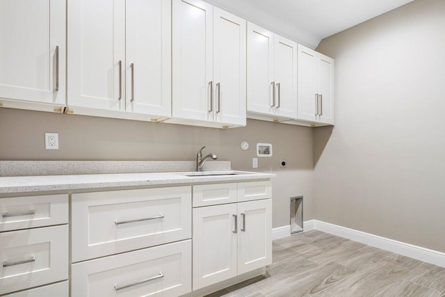 clothes washing area with cabinet space, baseboards, a sink, washer hookup, and electric dryer hookup